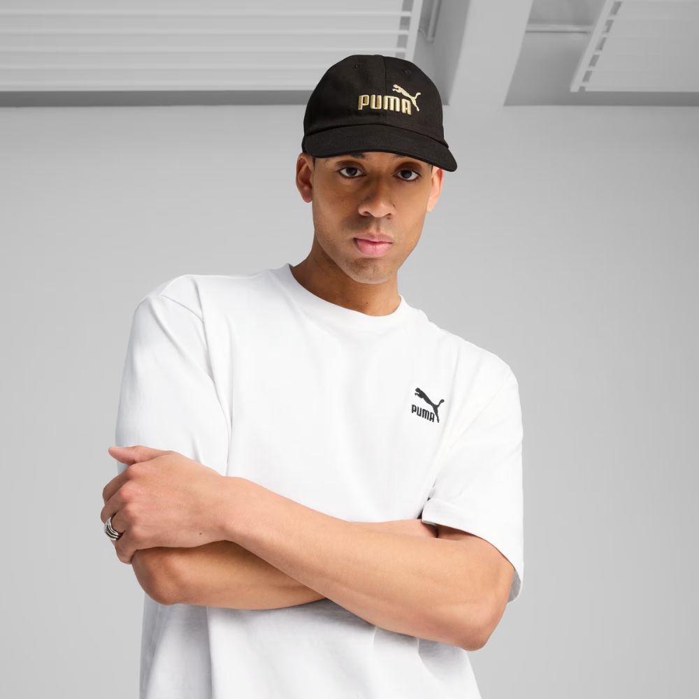 Modelo usando jockey Puma Essentials No.1 Logo negro con bordado dorado, vista frontal