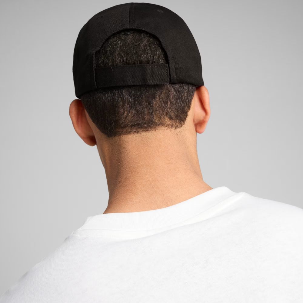 Modelo de espaldas usando jockey Puma Essentials negro con correa posterior ajustable
