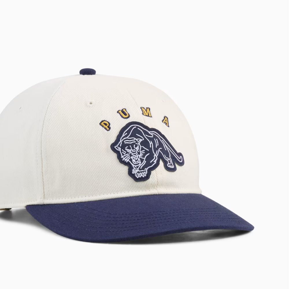Detalle del parche de felino y letras PUMA bordadas en el jockey Vintage Low Curve blanco con visera azul marino
